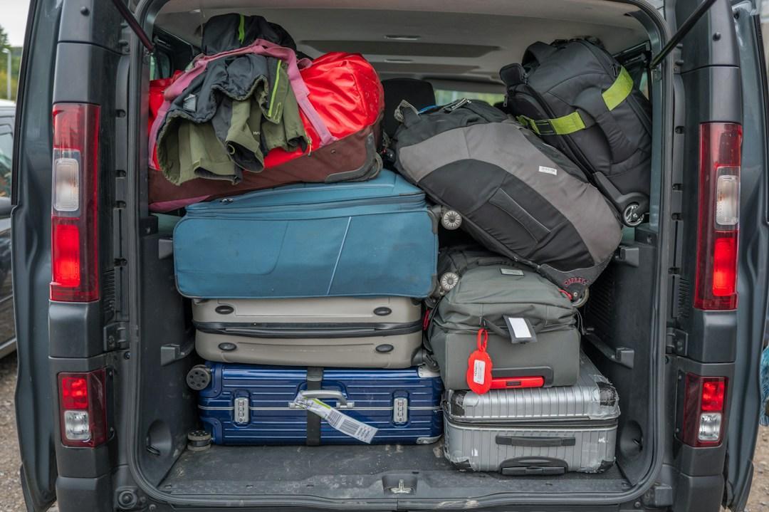 The open rear of a van packed with suitcases, duffel bags and backpacks
